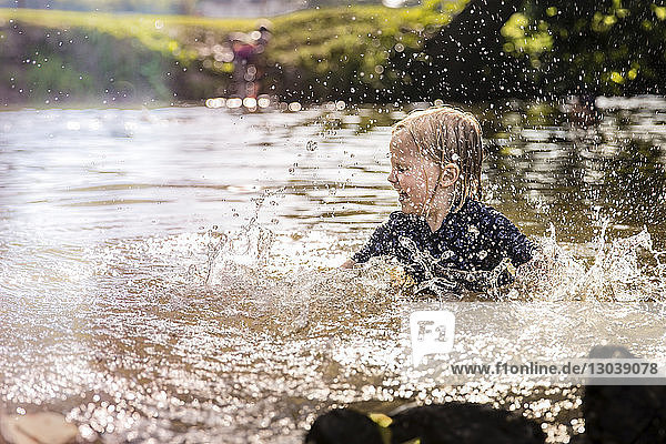 Carefree girl splashing water while playing in lake