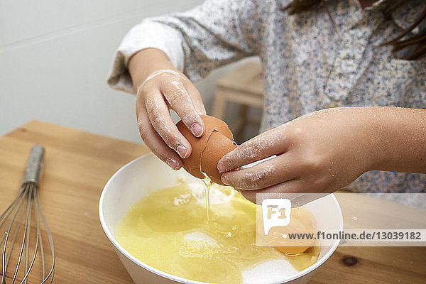 Ausgeschnittenes Bild eines Mädchens  das bei Tisch Eier in einer Schüssel zerbricht