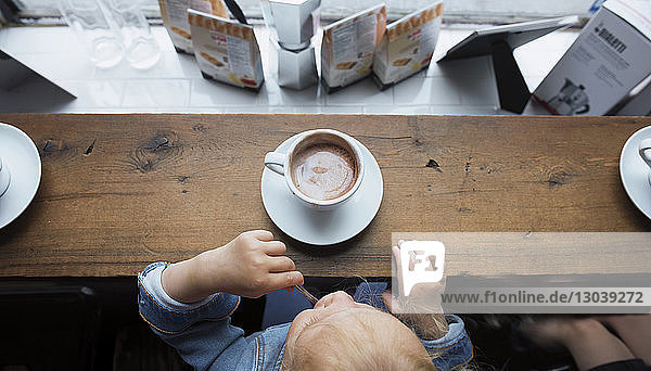 Draufsicht eines Mädchens beim Kaffeetrinken im Restaurant