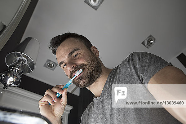 Niedrigwinkelansicht eines Mannes beim Zähneputzen im Badezimmer