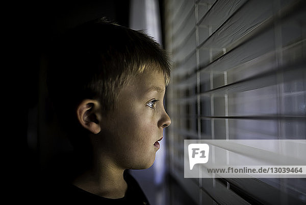 Nachdenklicher Junge schaut durch Fensterläden