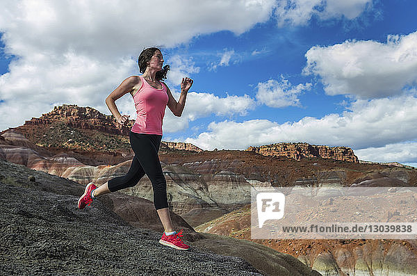 Woman jogging on field against cloudy sky