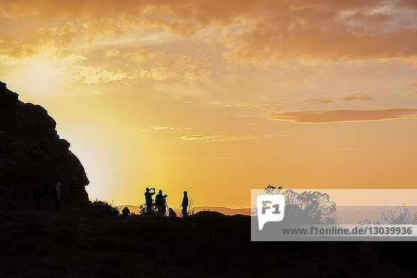 Scherenschnitt-Männer stehen bei Felsformation vor dramatischem Himmel im Arches-Nationalpark