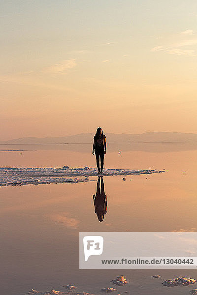 Frau steht bei Sonnenuntergang am Ufer des Großen Salzsees
