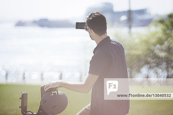 Seitenansicht eines Mannes  der mit einem Smartphone fotografiert  während er auf einem Citi Bike sitzt