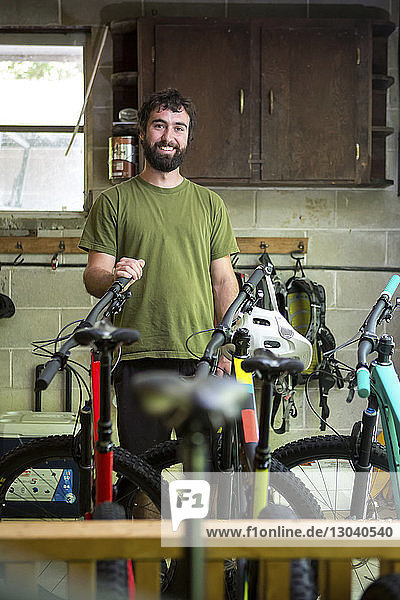 Porträt eines lächelnden Mechanikers  der im Fahrradladen steht