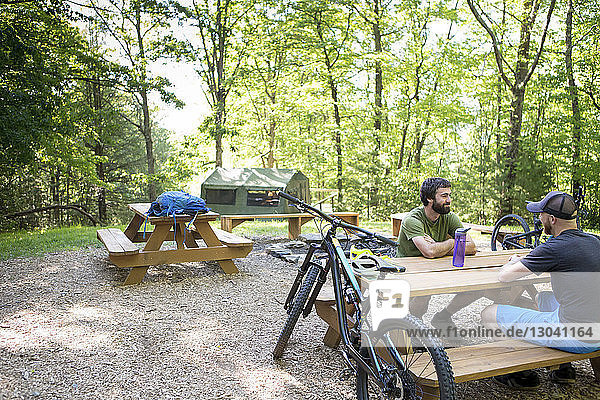 Männliche Wanderer sitzen auf dem Picknicktisch des Campingplatzes