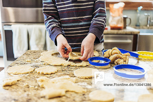 Midsection of boy making cookies at home