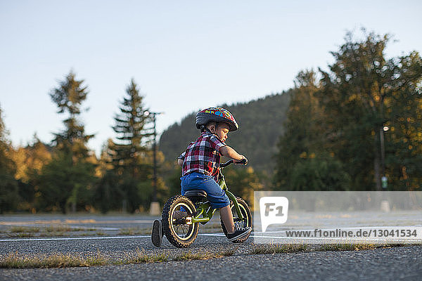 Junge in voller Länge mit Fahrradhelm beim Radfahren im Park