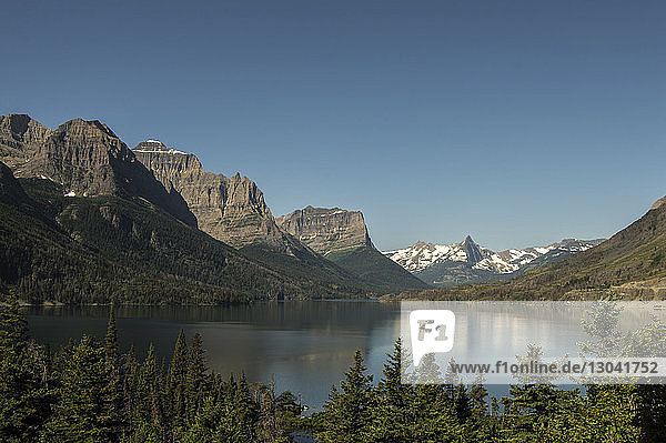 Panoramablick auf den See inmitten der Berge bei strahlend blauem Himmel im Glacier National Park
