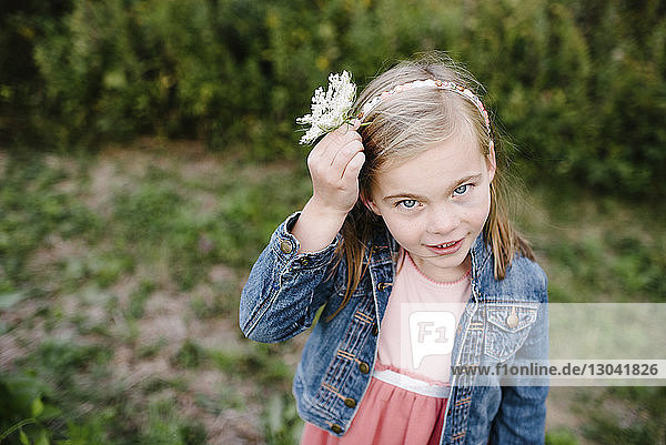 Hochwinkelporträt eines Mädchens  das eine Blume trägt  während es auf einem Feld im Park steht