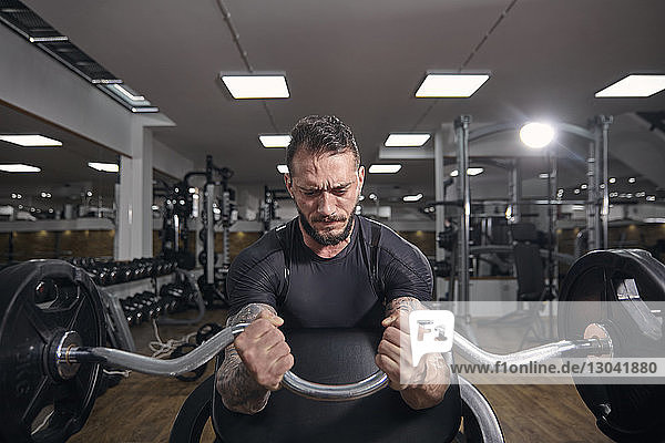 Muskulöser Mann hebt Langhantel beim Training im Fitnessstudio