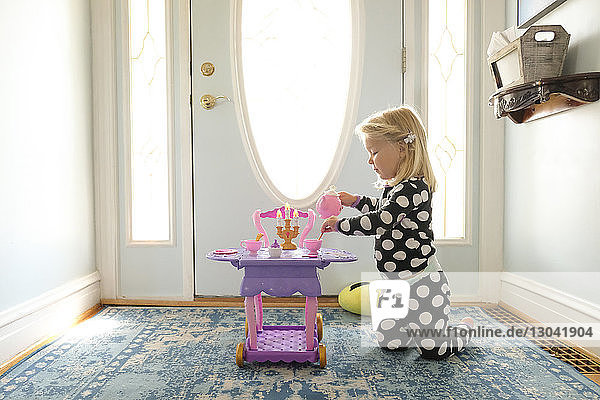 Seitenansicht eines Mädchens  das zu Hause am Eingang mit Spielzeug spielt