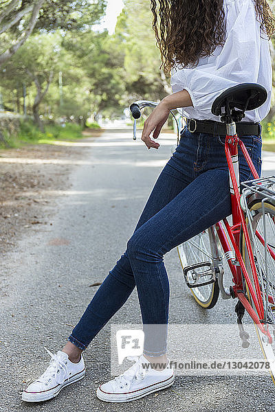 Low section of woman with bicycle on road
