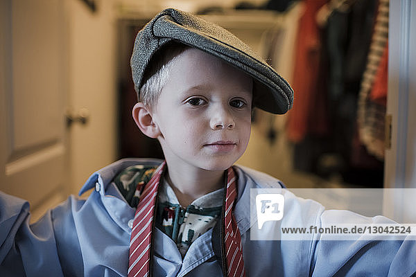 Porträt eines Jungen in Hemd und Krawatte mit Mütze  der zu Hause steht