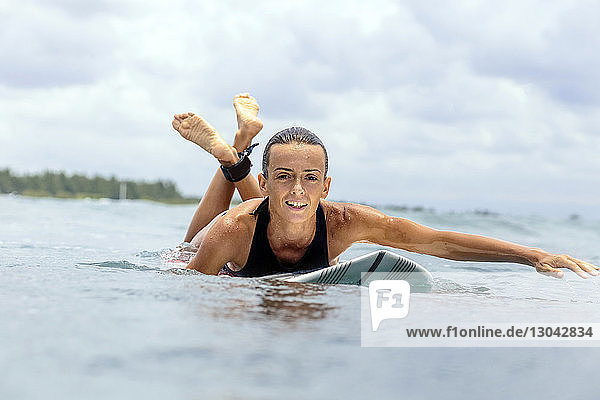 Porträt einer Frau beim Surfen vor bewölktem Himmel