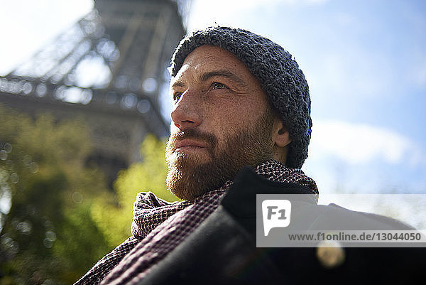 Low angle view of thoughtful male tourist against Eiffel Tower during sunny day