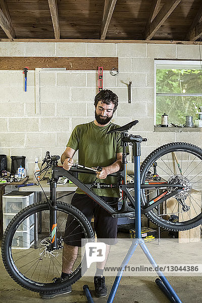 Mechaniker schaut weg  während er beim Mountainbike im Fahrradladen steht