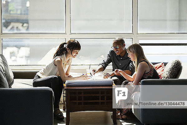 Business people checking blue prints on table in creative office