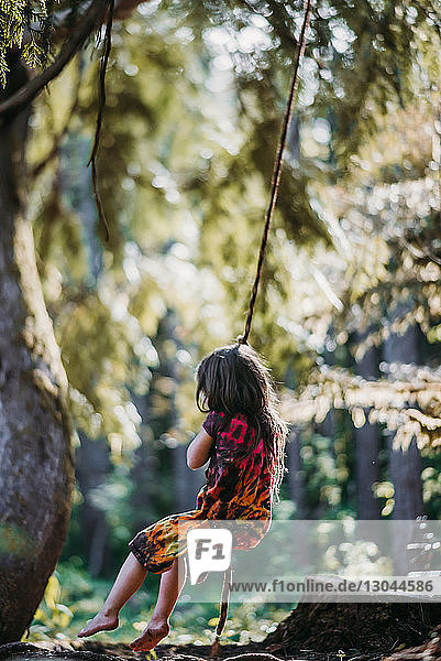Mädchen schwingt auf Seilschaukel im Wald