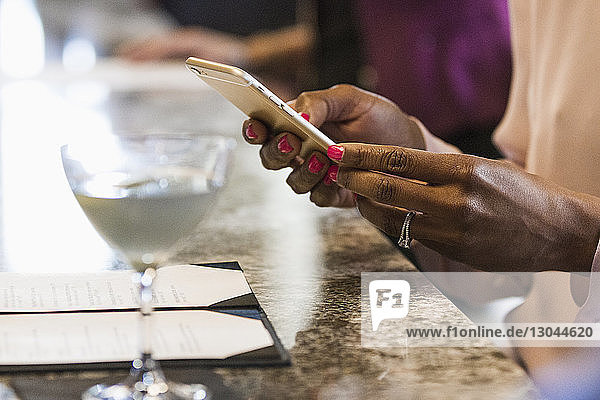 Abgetrennte Hände einer Geschäftsfrau mit Smartphone im Hotel