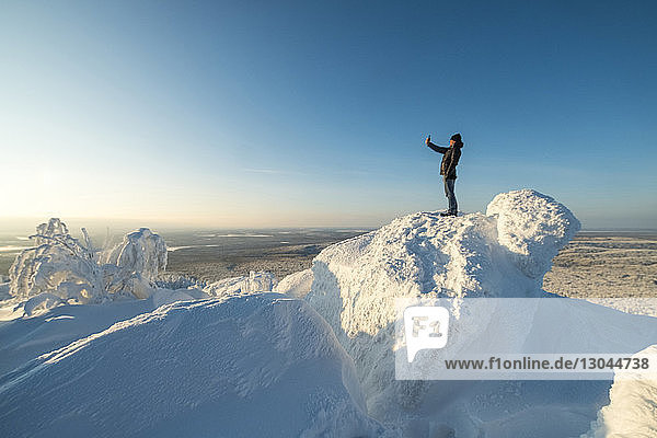Seitenansicht eines Selbstmordes eines Mannes  der auf einem schneebedeckten Berg vor blauem Himmel steht