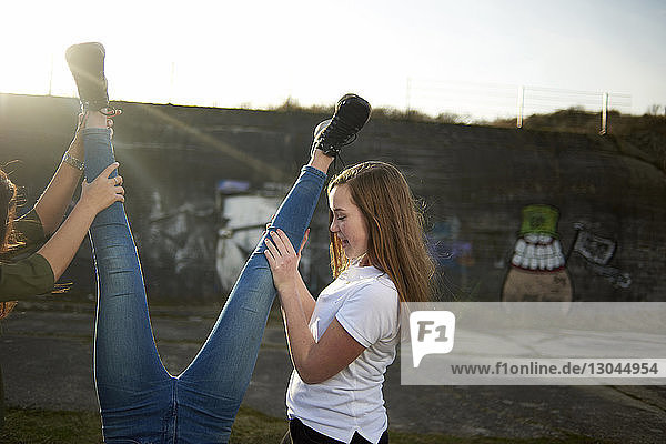 Verspielte Freunde halten Teenager-Mädchen an den Beinen