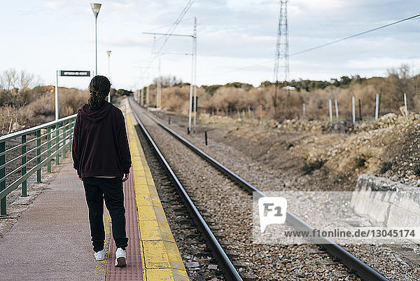 Full length rear view of teenage girl walking on railroad station platform
