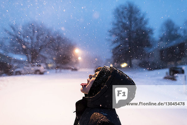 Verspielter Junge fängt Schneeflocken auf der Zunge