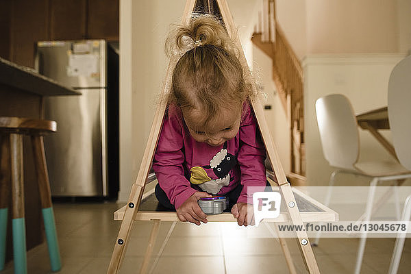 Süßes Mädchen kniend in Holzkonstruktion zu Hause