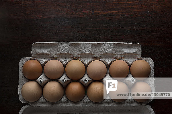 Draufsicht auf braune Eier im Karton auf dem Tisch