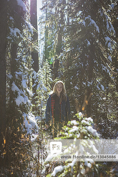 Portrait of female hiker standing in forest during winter