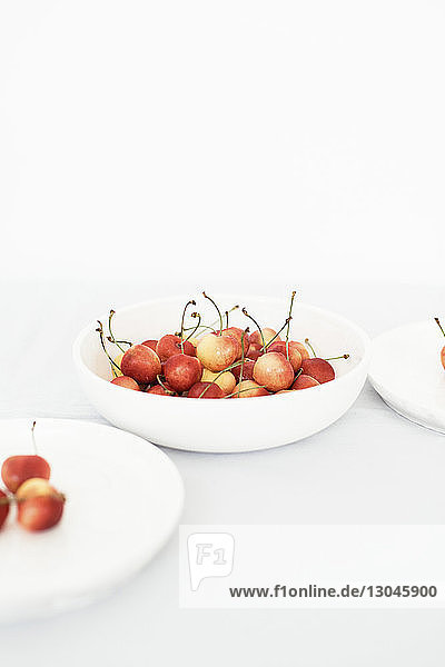 Hochwinkelansicht von Kirschen in Tellern vor weißem Hintergrund