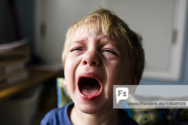 Close-up of boy crying at home