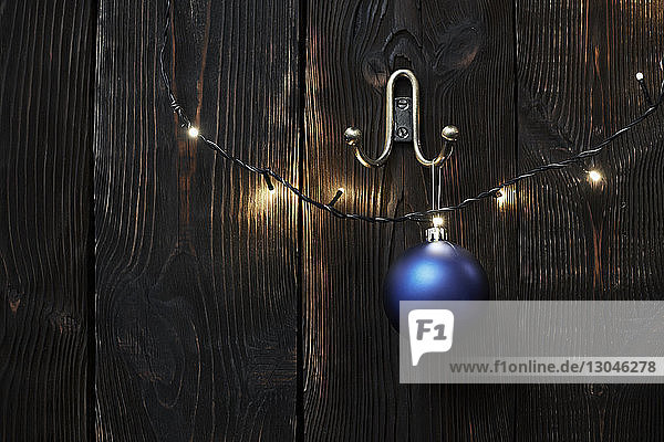 Weihnachtsbeleuchtung und Weihnachtskugel an der Holzwand