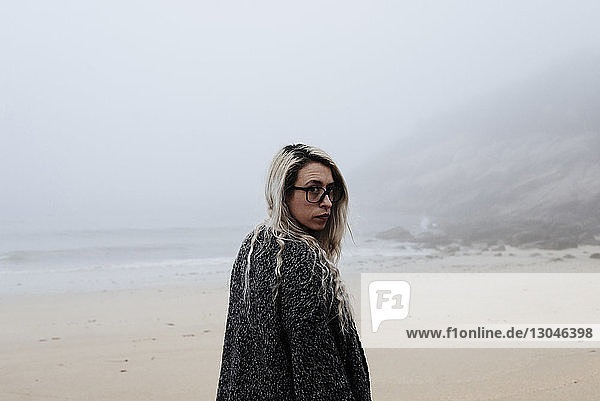 Portrait of woman standing at beach during foggy weather