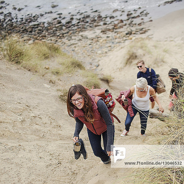 Glückliche Frau geht mit Freunden am Strand im Sand spazieren