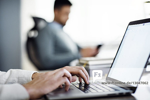 Cropped image of businessman using laptop in creative office