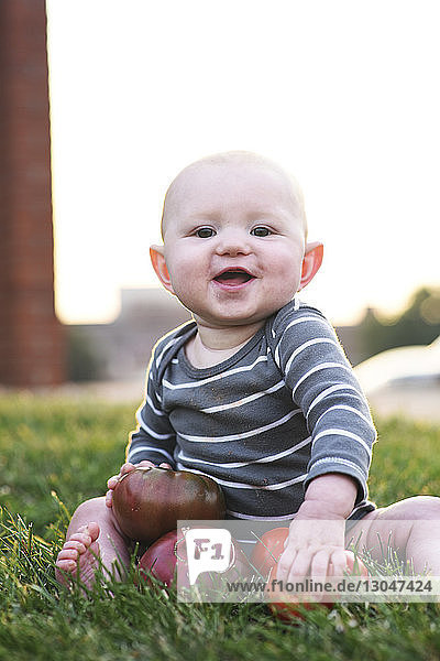 Porträt eines süßen kleinen Jungen  der im Garten mit frischen Tomaten spielt