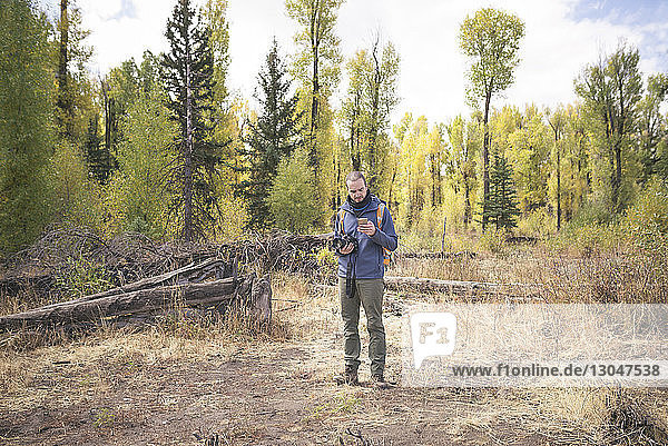Wanderer benutzt Mobiltelefon  während er auf einem Feld im Wald steht
