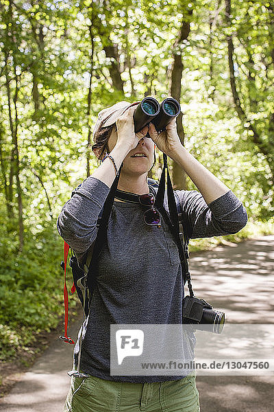 Hiker - looking through binoculars while standing in forest at Redwood National and State Parks