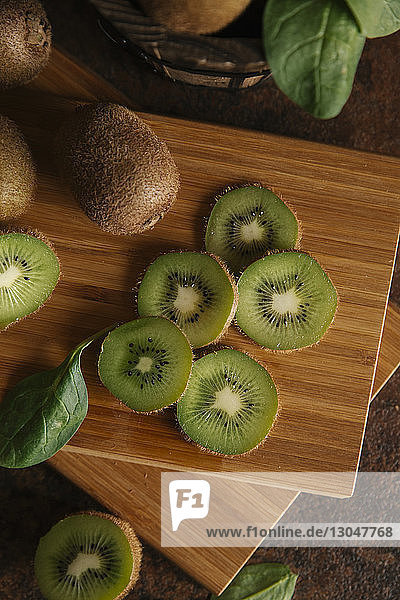 Hochwinkelansicht von Kiwifrüchten auf Schneidebrett am Tisch