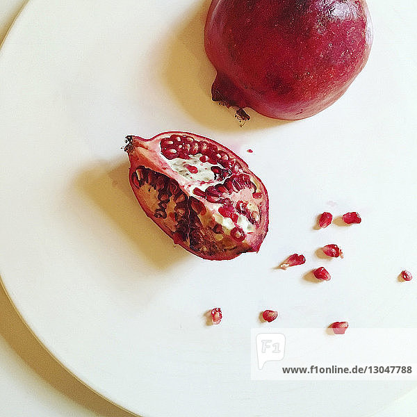 Hochwinkelansicht eines Granatapfels in weißer Platte auf dem Tisch