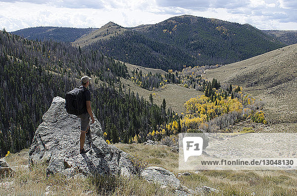 Wanderer schaut auf Berge  während er auf Fels steht