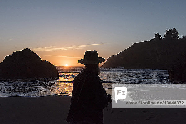 Silhouettenmann steht bei Sonnenuntergang am Strand