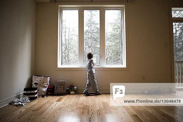 Junge in voller Länge zu Hause am Fenster stehend
