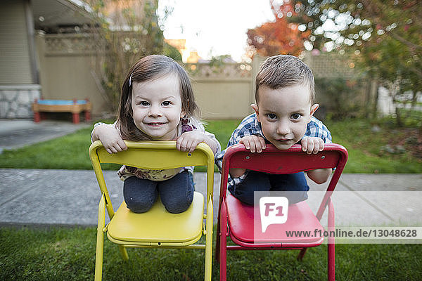Porträt von Geschwistern kniend auf Stühlen im Hof
