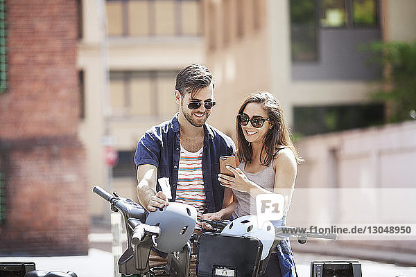 Junges Paar benutzt Smartphone im Stehen mit Fahrrädern