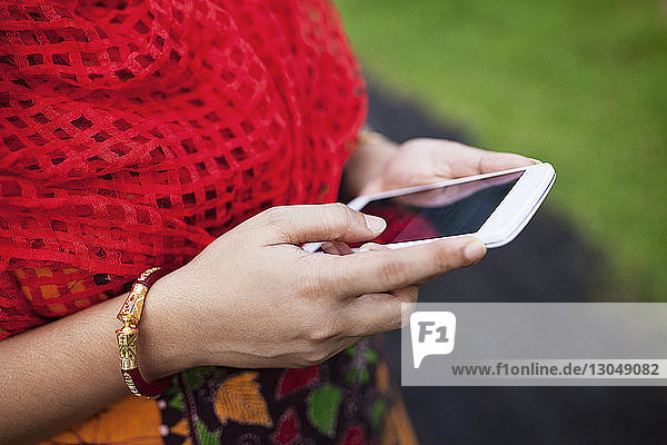Midsection of woman using smart phone on field