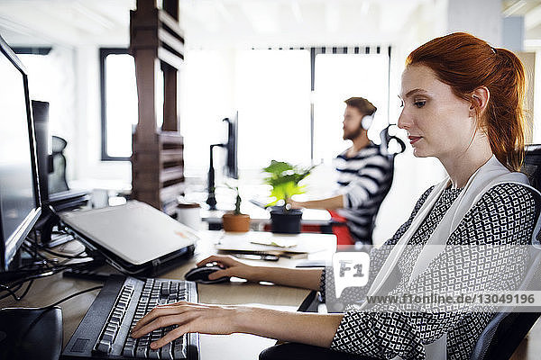 Seitenansicht einer Geschäftsfrau  die einen Computer im Kreativbüro benutzt